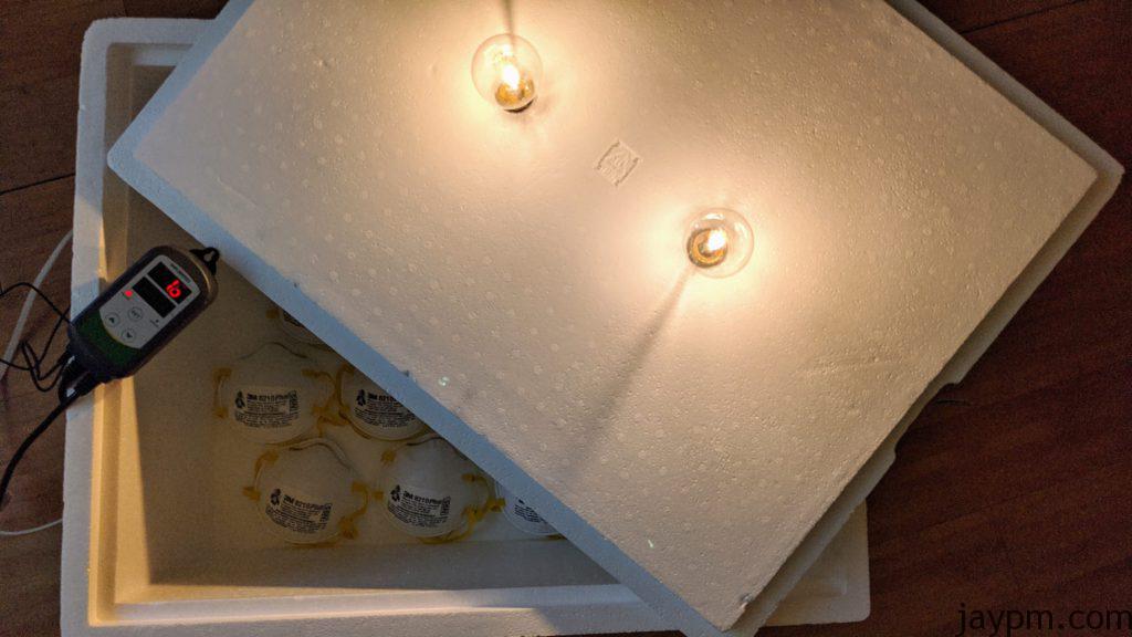 Two lightbulbs are mounted through the styrofoam cover